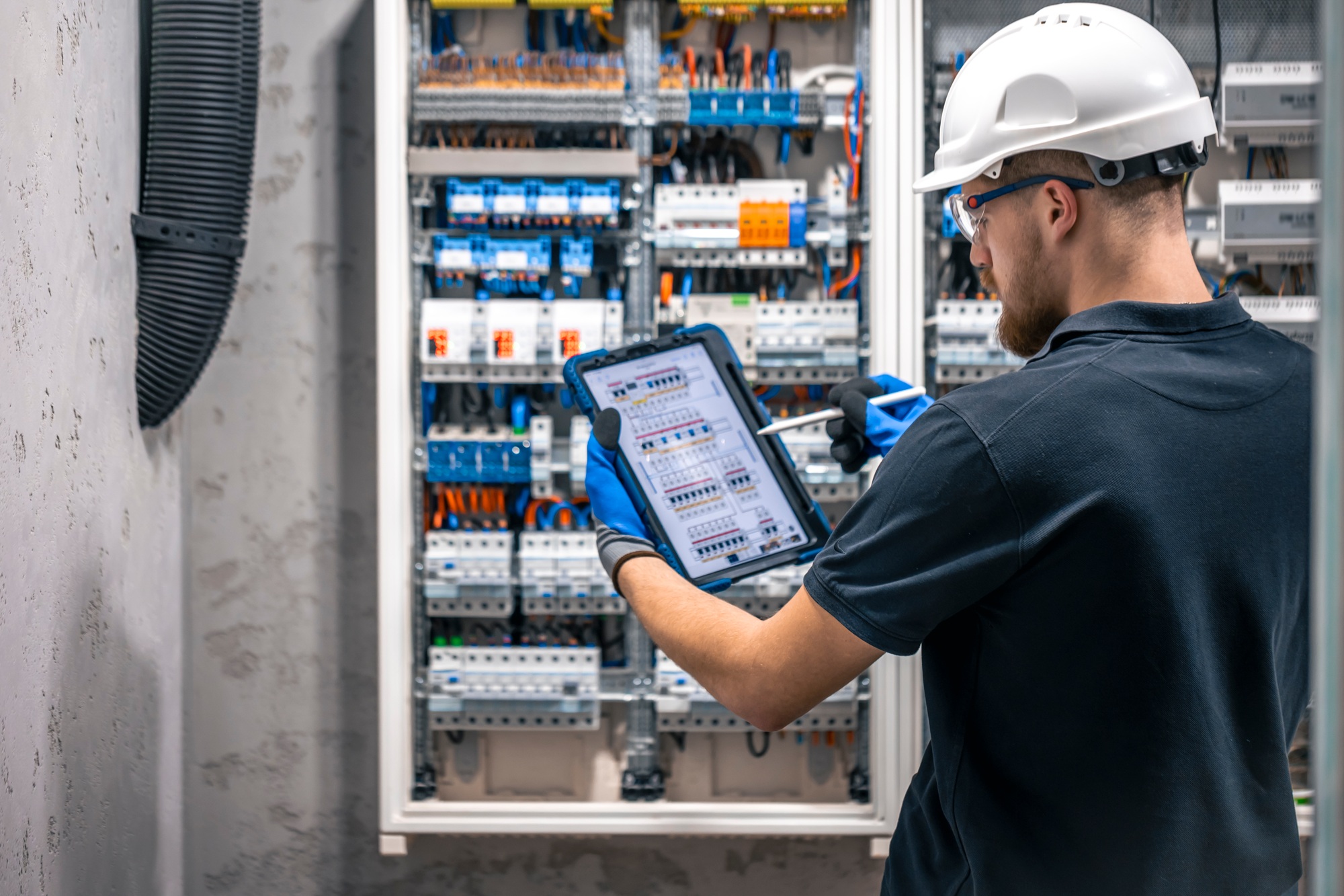 Electrician with tablet adjusting circuitry at junction box.